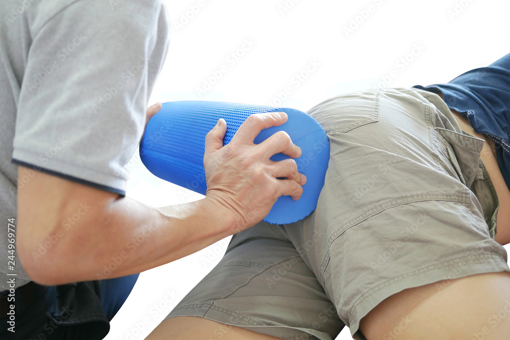 Obraz premium Physical therapist treats patient bottoms physio massage by blue foam roller to decrease pain and improve mobility