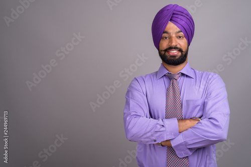 Young handsome Indian Sikh businessman wearing turban against gr photo