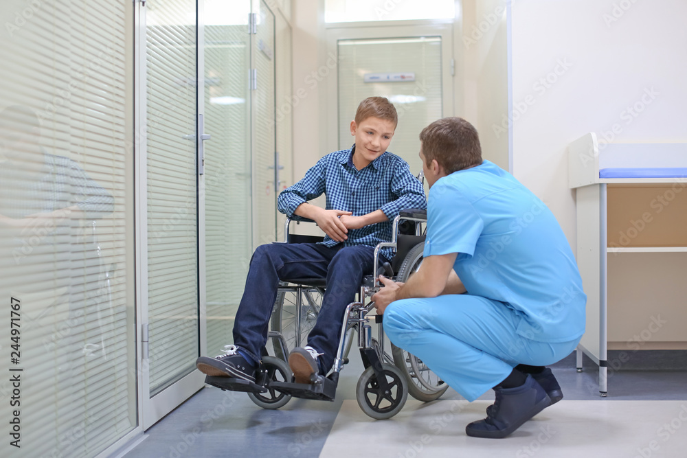 Male doctor taking care of little boy in wheelchair indoors Male doctor taking care of little boy in wheelchair indoors