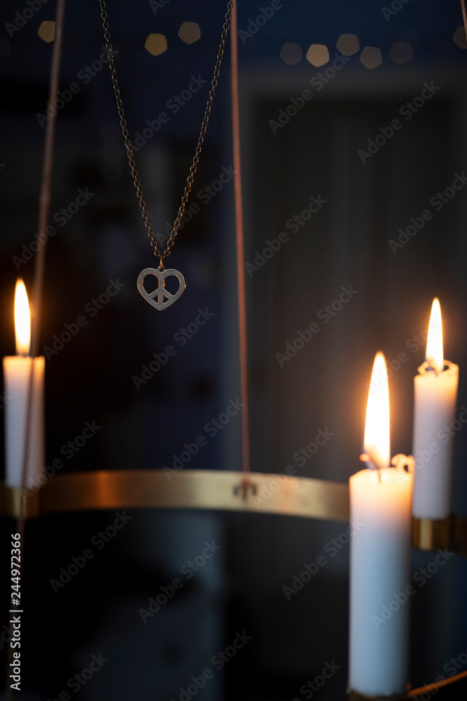 Peace heart symbol necklace and candles glowing on advent chandelier. Peace heart symbol necklace and candles glowing on advent chandelier.