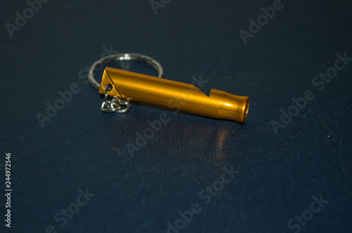 golden whistle on keychain, for adventure Trekking, isolated on blue background photo