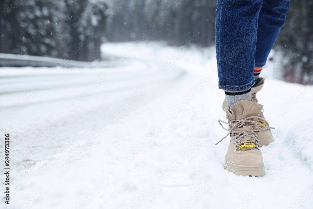 Woman walking outdoors on snowy winter day. Space for text