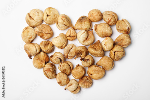 Heart shaped heap of dried figs on white background, top view. Healthy fruit