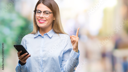 Young beautiful business woman texting message using smartphone over isolated background very happy pointing with hand and finger to the side