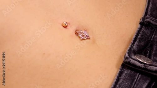 slow motion closeup piercing master in gloves wipes skin with cotton napkin around gold sparkling belly button ring 