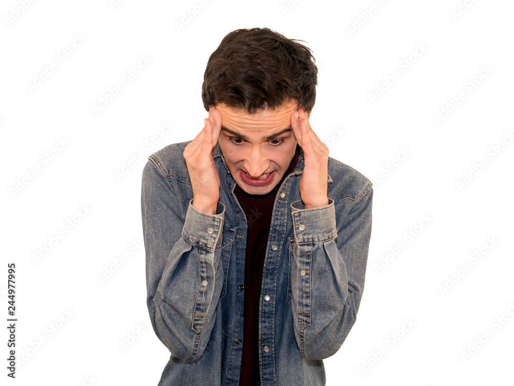 Young stressful man suffers from headache, keeps hands on temples, clenched teeth, has terrible pain, dressed in denim shirt, isolated over grey background Young stressful man suffers from headache, keeps hands on temples, clenched teeth, has terrible pain, dressed in denim shirt, isolated over grey background