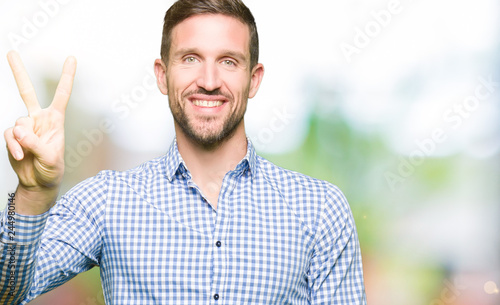 Handsome business man with blue eyes showing and pointing up with fingers number two while smiling confident and happy.