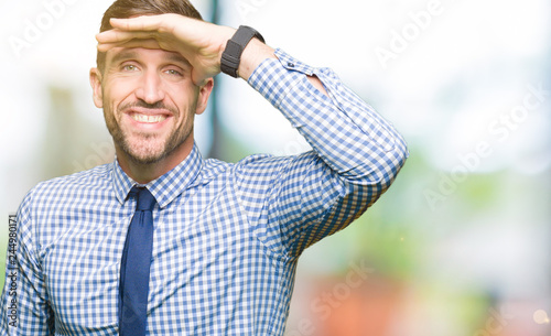 Handsome business man wearing tie very happy and smiling looking far away with hand over head. Searching concept.
