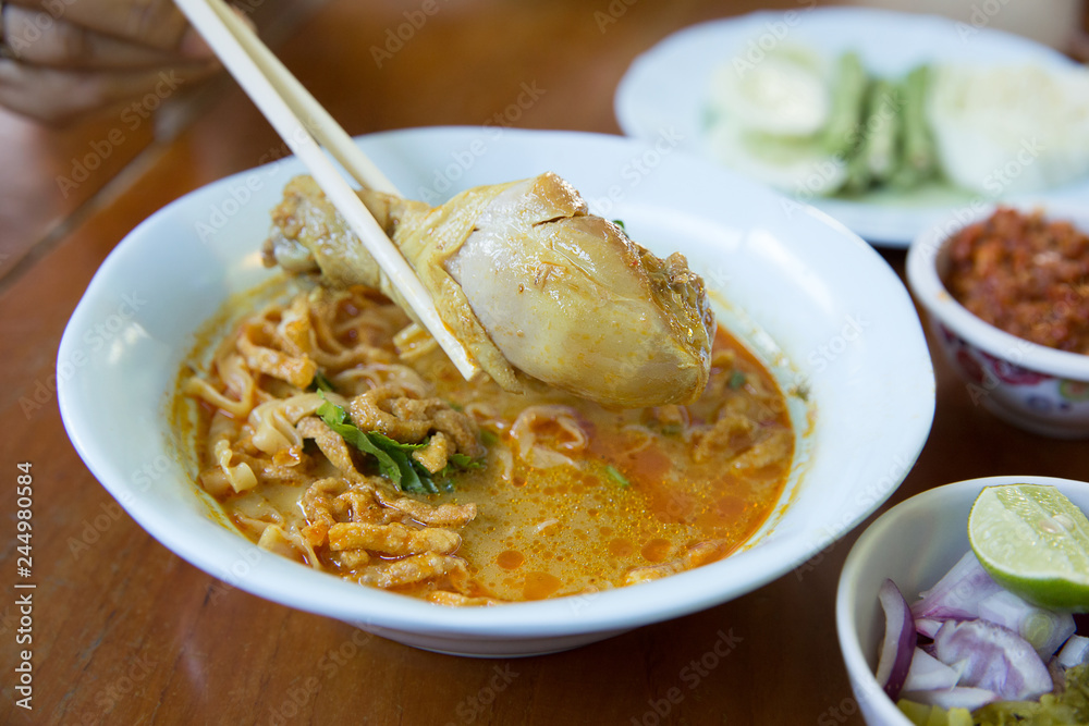 Khao Soi , Northern Thai Style Curried Noodle Soup with Chicken on wood background Khao Soi , Northern Thai Style Curried Noodle Soup with Chicken on wood background
