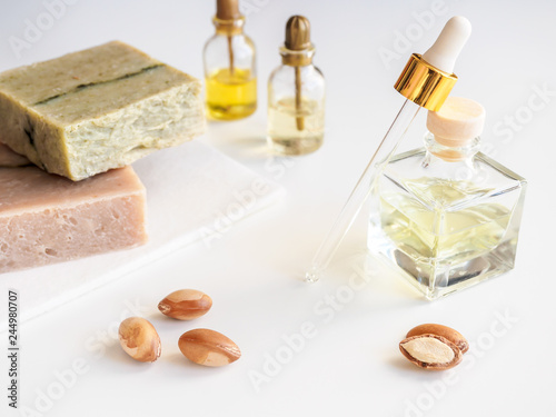 Bottles with valuable cosmetic oil argan nuts. Cosmetic means. Food product. Jar with argan oil and handmade soap on the isolated background