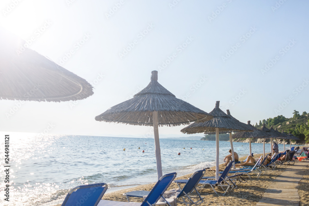 Umbrellas and deck chairs arranged in the row by the sea on the beach
