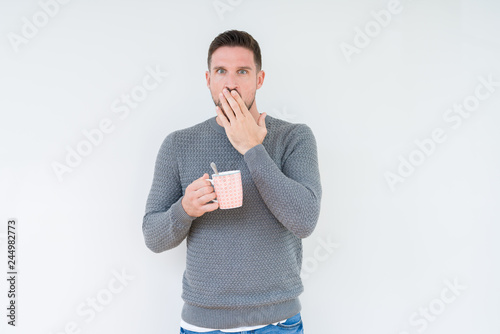 Young man driking cup of coffee over isolated background cover mouth with hand shocked with shame for mistake, expression of fear, scared in silence, secret concept