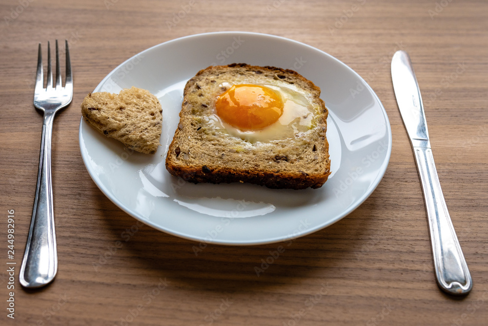 Breakfast concept. White plate with hearts of bread, baked bread and egg. Wooden texture background. Breakfast concept. White plate with hearts of bread, baked bread and egg. Wooden texture background.