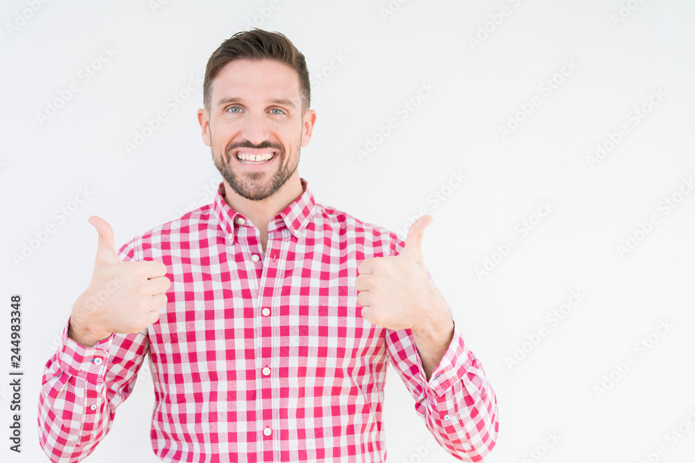 Young handsome man wearing shirt over isolated background success sign doing positive gesture with hand, thumbs up smiling and happy. Looking at the camera with cheerful expression, winner gesture. Young handsome man wearing shirt over isolated background success sign doing positive gesture with hand, thumbs up smiling and happy. Looking at the camera with cheerful expression, winner gesture.