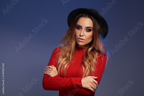 Portrait of wonderful white female model with bright makeup expressing energy on blue background. Lovely curly woman in stylish black hat © oes
