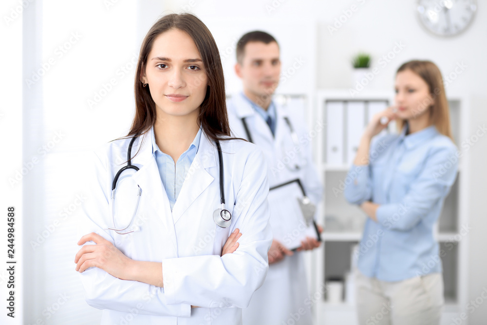 Young beautiful female doctor smiling on the background with patient in hospital Young beautiful female doctor smiling on the background with patient in hospital