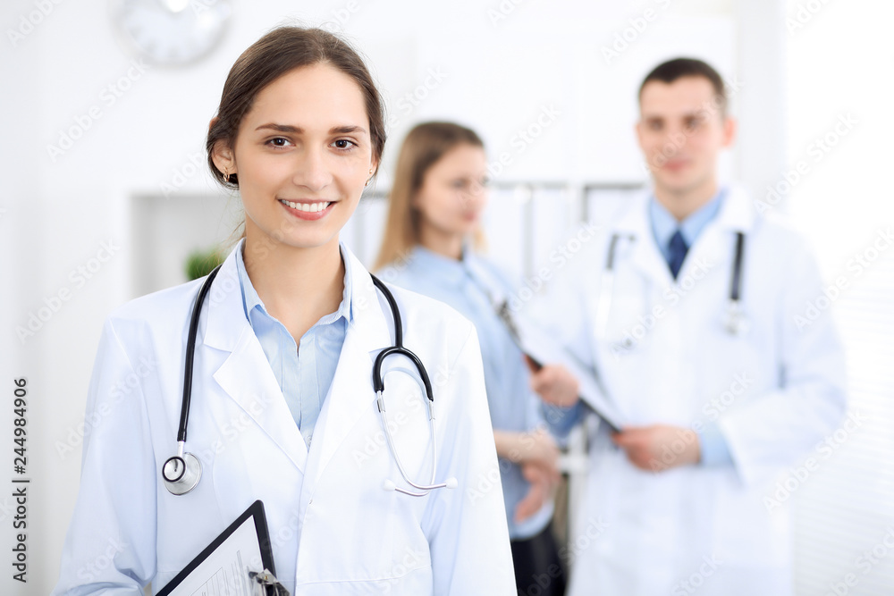 Young beautiful female doctor smiling on the background with patient in hospital Young beautiful female doctor smiling on the background with patient in hospital
