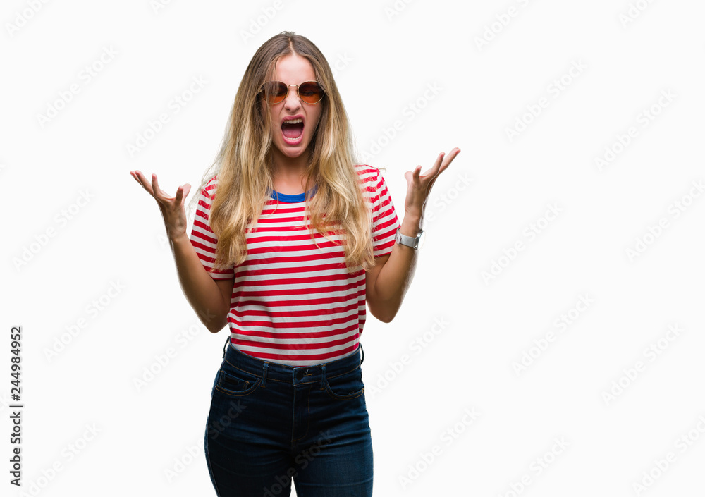 Young beautiful blonde woman wearing sunglasses over isolated background celebrating mad and crazy for success with arms raised and closed eyes screaming excited. Winner concept Young beautiful blonde woman wearing sunglasses over isolated background celebrating mad and crazy for success with arms raised and closed eyes screaming excited. Winner concept