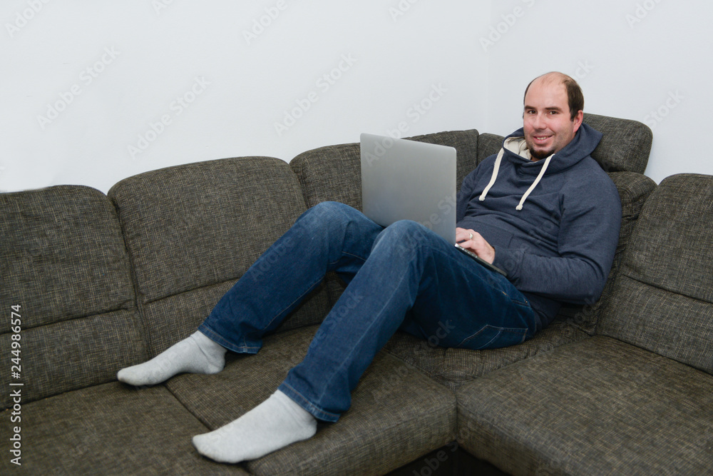 Mann arbeitet von zu Hause am Laptop auf der Couch