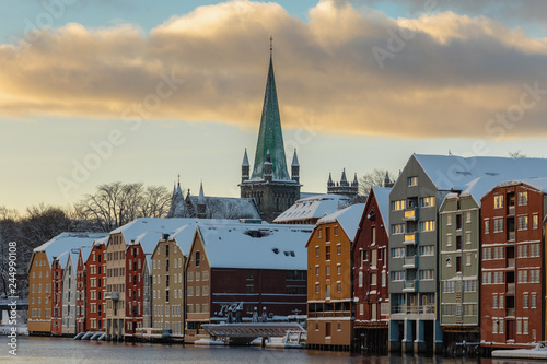 Old houses and magazines by Nidelva river in Trondheim, Nidarosdomen Cathedral in back.