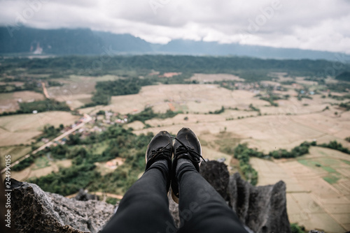 Hanging the legs down on top of the mountain with rice field view.