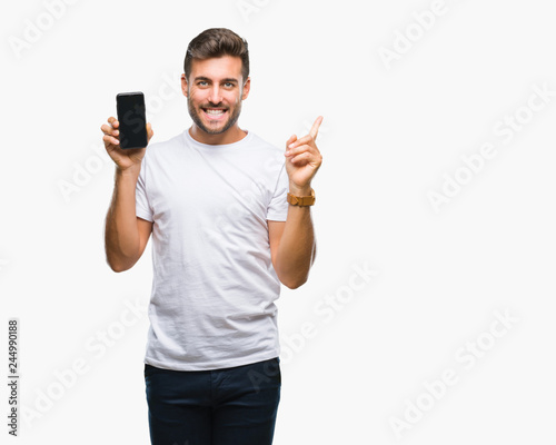 Young handsome man showing smartphone screen over isolated background very happy pointing with hand and finger to the side