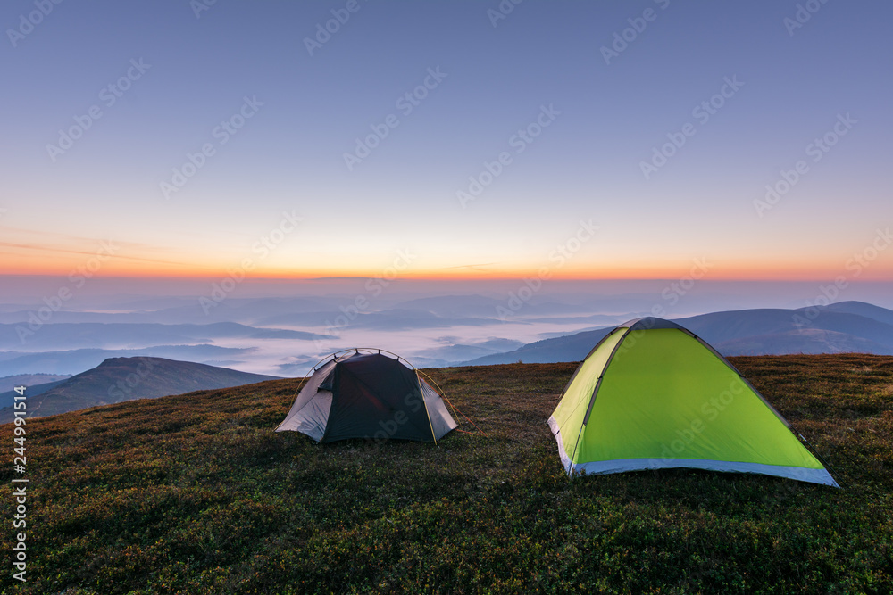 Girls on a mountain ridge rest with tents.