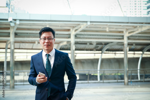 Asian business men Wearing a suit, standing, holding the phone Have space to write messages