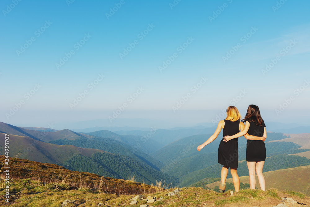 Girls on a mountain ridge rest with tents.