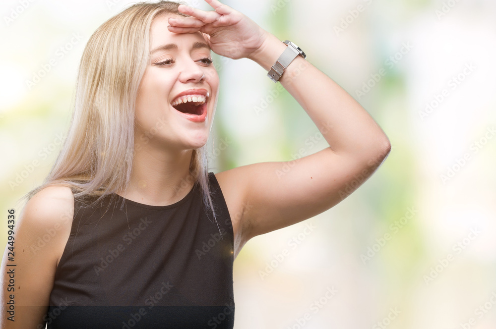 Young blonde woman over isolated background very happy and smiling looking far away with hand over head. Searching concept.