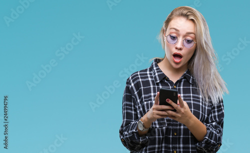 Young blonde woman texting sending message using smartphone over isolated background scared in shock with a surprise face, afraid and excited with fear expression