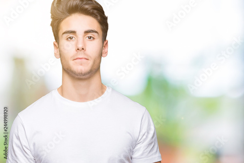 Young handsome man wearing white t-shirt over isolated background Relaxed with serious expression on face. Simple and natural looking at the camera.