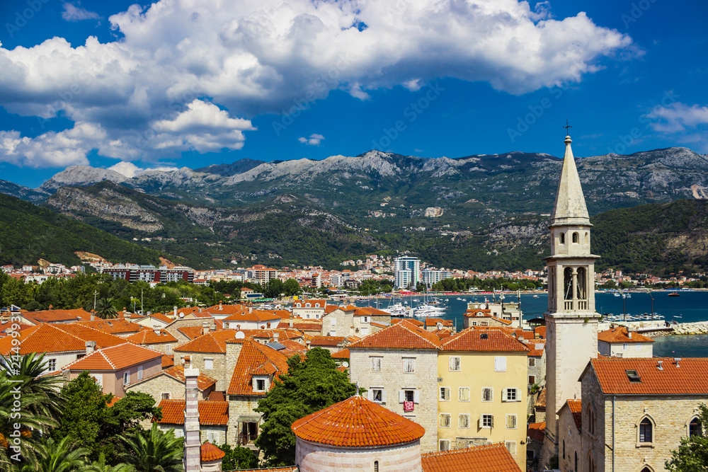 View of the old town of Budva in Montenegro. Summer day and clouds over the mountains in the background. Soft focus and blur.