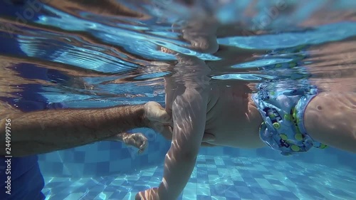 Happy smiling toddler is diving under water with father