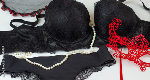 Sexy female black lace underwear. Bra, panties, lace red mask and pearls on a white background.