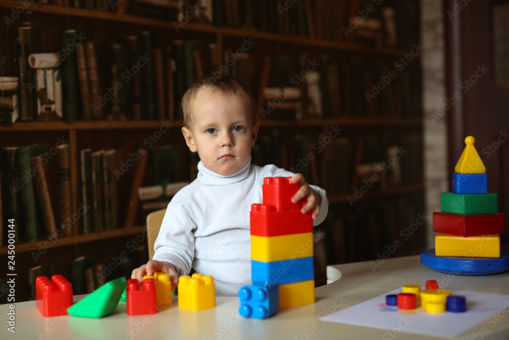 Toddler child builds tower sits at table Toddler child builds tower sits at table