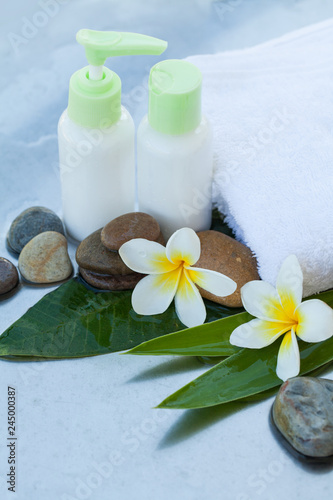 Spa background with green leaves  stones  flowers and cosmetics treatment