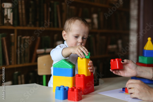 Toddler with mother plays with plastic constructor