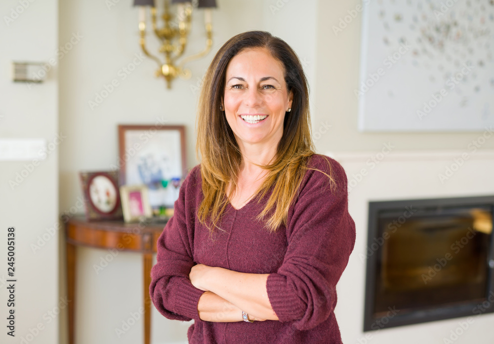 Beautiful middle age woman smiling with crossed arms at home Beautiful middle age woman smiling with crossed arms at home
