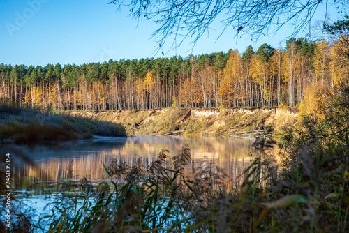 blue sky and clouds reflecting in calm water of river Gauja in latvia in autumn