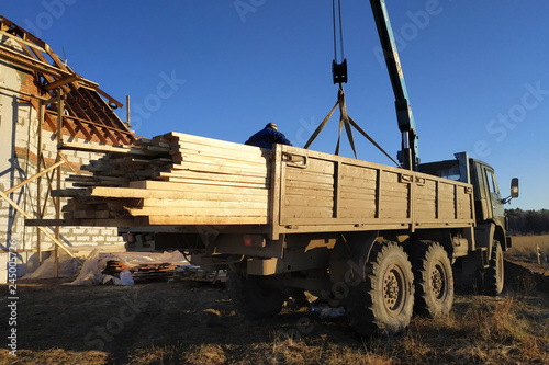 Unloading boards from the side of the crane with the help of people