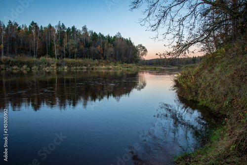 blue sky and clouds reflecting in calm water of river Gauja in latvia in autumn