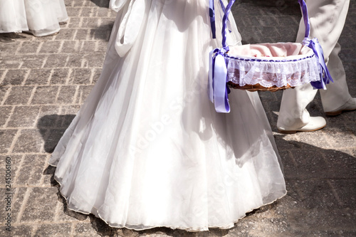 niñas llevando vestidos de comunión  blancos y largos con cesto lazos morados photo