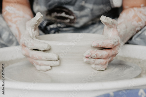 Creating a jar or vase of white clay close-up. Woman hands making clay jug.