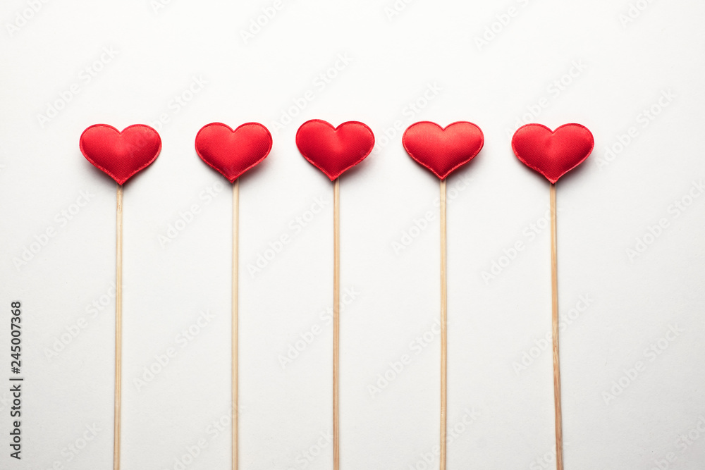 Red textile hearts on wooden sticks closeup. Valentines day background, creative texture and love concept