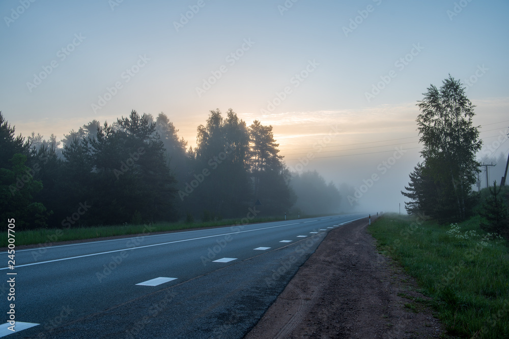 Fototapeta premium empty asphalt road with white lines painted in misty morning