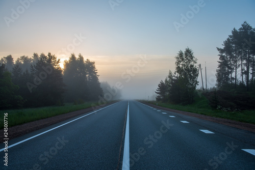 empty asphalt road with white lines painted in misty morning