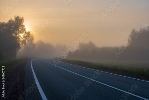 empty asphalt road with white lines painted in misty morning