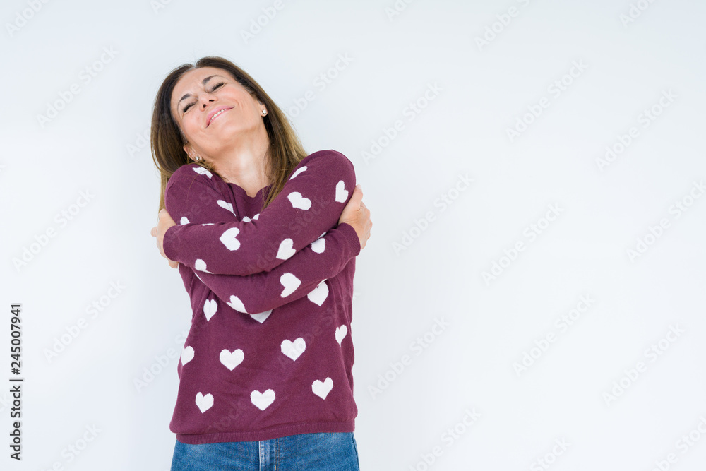 Beautiful middle age woman wearing heart sweater over isolated background Hugging oneself happy and positive, smiling confident. Self love and self care Beautiful middle age woman wearing heart sweater over isolated background Hugging oneself happy and positive, smiling confident. Self love and self care