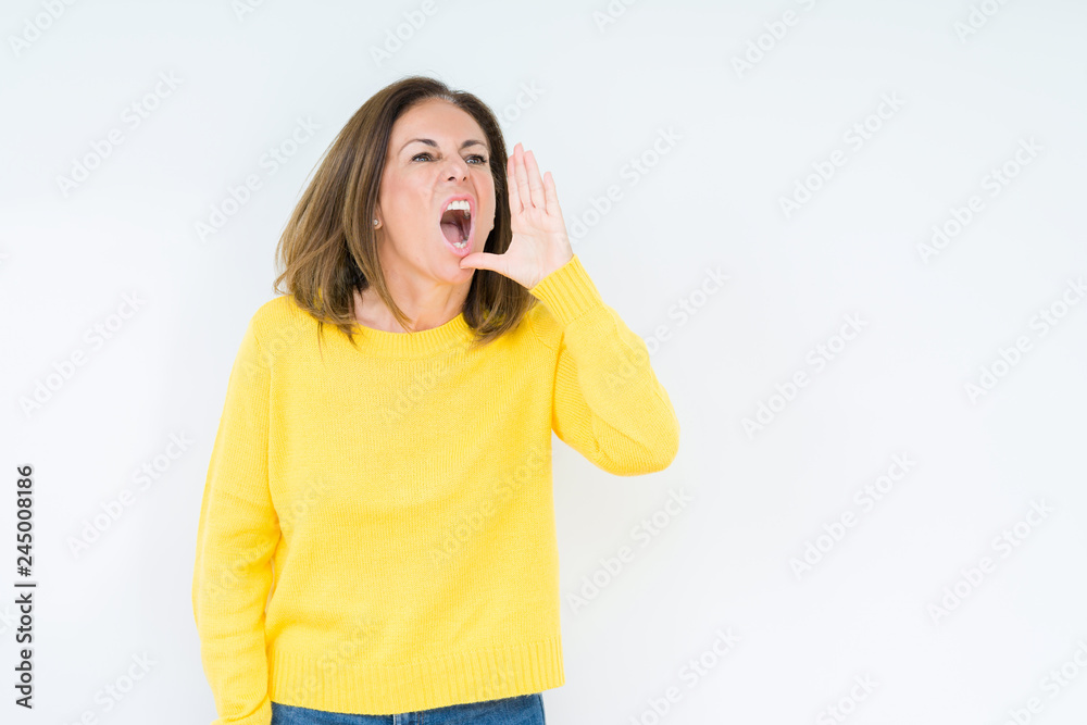 Beautiful middle age woman wearing yellow sweater over isolated background shouting and screaming loud to side with hand on mouth. Communication concept. Beautiful middle age woman wearing yellow sweater over isolated background shouting and screaming loud to side with hand on mouth. Communication concept.